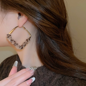Close-up of geometric diamond earrings with brown leopard print and gold metal finish
