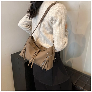 Borsa a spalla marrone in finta pelle con frange e borchie indossata da una modella