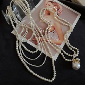 Elegant multi-layer pearl necklace with a large statement pearl pendant on black fabric