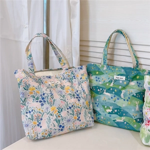 Détail de sacs fourre-tout en toile à motifs floraux et lapins avec étiquettes tissées