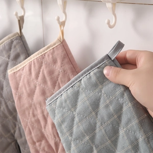 Detail of quilted cotton heat resistant oven mitts in grey, pink, and blue with hanging loops