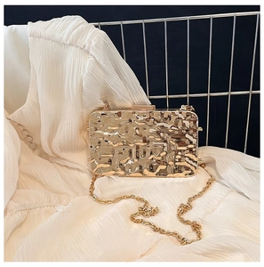 Detail of metallic pleated evening clutch with golden chain strap and textured surface