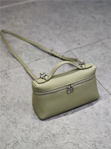Detail of pistachio green pebbled leather handbag with silver lock and zipper closure