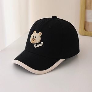 Détail de la broderie d'ours sur une casquette en coton noir et beige pour bébés