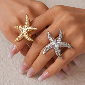 Detailed view of large gold and silver starfish rings worn on model fingers