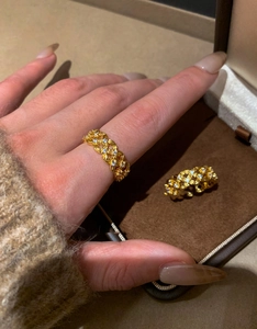 Close-up of gold plated hollow woven ring with micro-set zircons on index finger