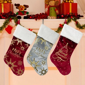 Trois chaussettes de Noël en velours rouge et argent avec motifs festifs dorés