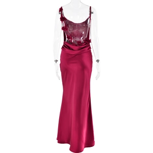 Détail d'une robe de soirée en satin rouge foncé avec fleurs 3D et texture froncée