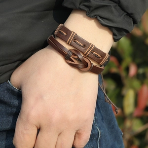 Detail of male model wearing vintage braided brown leather bracelet set in outdoor sunlight