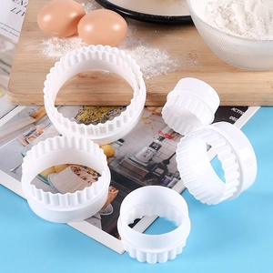 Detail view of 5-piece white plastic round pastry cutters with scalloped edges in baking setting