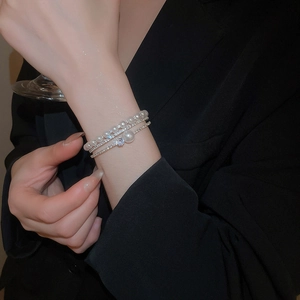 Close-up of multilayered silver bracelet with pearls and sparkling rhinestones on wrist