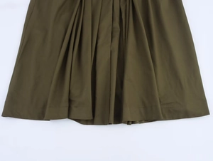 Détail de la robe midi plissée vert olive montrant les plis verticaux et le tissu texturé