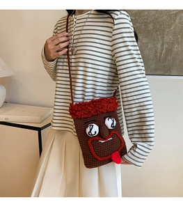 Braune lustige Strickumhängetasche mit großen Augen und Wurstlippen an einem Modell