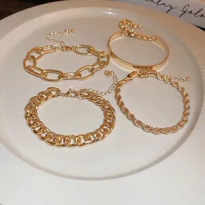 Four-piece gold layering bracelet set featuring cuban, curb, and open cuff chain links