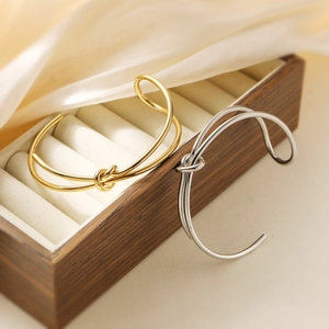Minimalistische knooparmbanden in goud en zilver gepresenteerd in een luxe sieradendoos