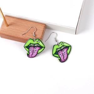Macro shot of quirky green lips and purple tongue acrylic earrings on a white stand