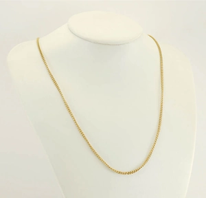 Detailed view of a slim gold curb chain necklace displayed on a white jewelry mannequin