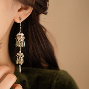 Close-up of vintage gold tassel earrings with grey beads worn by a model