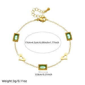 Detail of gold chain bracelet featuring green rectangle gems and hollow heart charms
