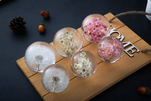Detail of crystal resin dandelion balls with dried flowers on a rustic wooden stand