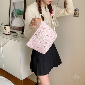 Detailed shot of pink quilted cosmetic bag with cute bear and donut prints in hand