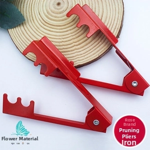 Detail view of two professional red iron rose thorn strippers on a rustic garden background