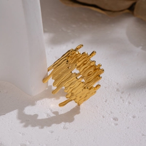 Minimalist gold irregular wave ring with lava texture leaning on white geometric props