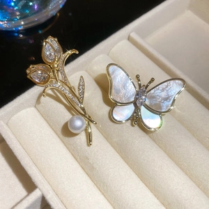Detail of 14K gold plated tulip and butterfly brooches with zircon and pearl in a velvet box