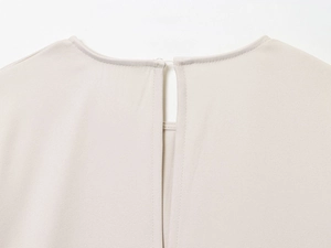 Close-up of beige blouse neckline with keyhole back closure and twill fabric texture
