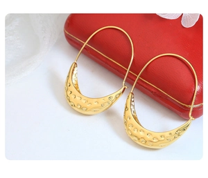 Detail of gold hammer textured crescent earrings with vintage aesthetic on lace background