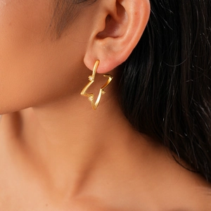 Detail of 18K gold-plated star hoop earring with clear zircons worn by a model