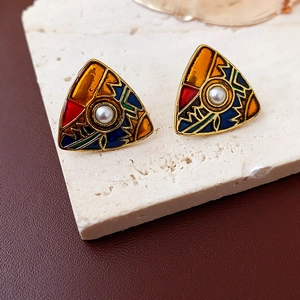 Macro detail of triangle vintage earrings with colorful enamel patterns and central pearl