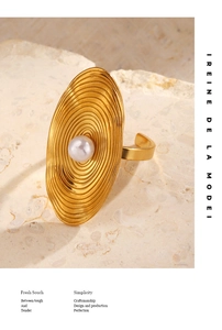 Detail of gold oval ring with concentric ripple texture and white pearl on stone