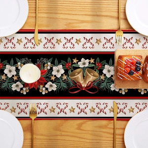 Christmas table runner with poinsettia and bell patterns on a festive wooden dinner table