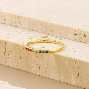 Detailed view of gold rainbow rhinestone ring on a beige travertine stone display