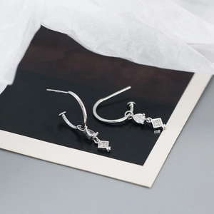 Detail of S925 silver hoop earrings with teardrop and square zircon charms on polaroid
