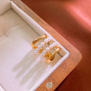 Dettaglio di un anello multistrato dorato con perle in una lussuosa scatola di legno