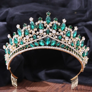 Detail of golden Baroque crown with green crystals and rhinestones on dark background