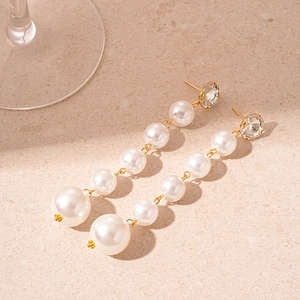 Detail of vintage long tassel earrings with white pearls and sparkling zircons on stone