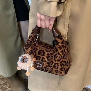 Fashionable leopard print handbag with brown handle and plush lion charm accessory