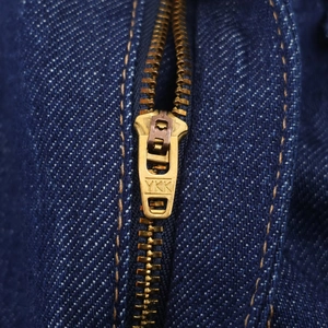 Gros plan sur la fermeture éclair YKK en laiton sur un tissu en denim bleu