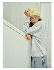 Detail of yellow cat ear knit hat paired with a light grey hoodie and blue skirt