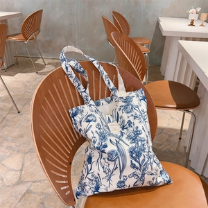 Detail view of the French floral canvas tote bag placed on a rustic wooden chair