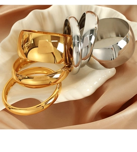 Detailed close-up of polished gold and silver steel bangles on silk and shell plate