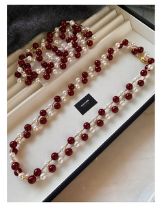 Vista dettagliata delle perle rosse vintage e delle perle color crema nella collana