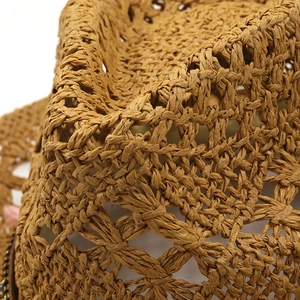 Macro shot of natural khaki straw cowboy hat with intricate hollow weaving and texture