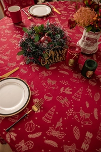 Detail of red Christmas tablecloth featuring golden festive bells and Ho Ho Ho patterns