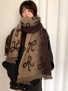 Detail of thick knitted scarf with bow pattern and tassel fringe in brown and beige