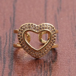 Dettaglio di un anello a cuore placcato oro con zirconi micro-pavé su sfondo di legno