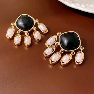 Detail of vintage gold earrings with black square stone and oval pearl drops
